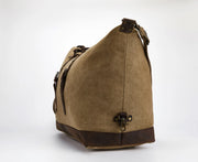 A brown canvas duffel bag with dark brown leather trim and a top handle, shown from a three-quarters angle on a light gray background.