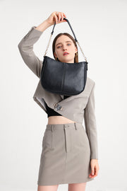 Black | Woman carrying the Harper black hobo bag with metal chain strap